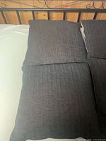 Four dark brown square pillows arranged together on a bed showing overall appearance and texture