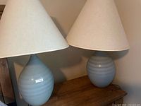 Pair of blue-grey ceramic lamps with cream shades on table