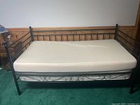 Overall view of black metal daybed with mattress and topper