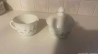 Sugar bowl with lid and creamer side by side displaying overall form and pattern.