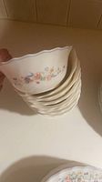 Stack of blue-rimmed Arcopal floral cereal bowls held for profile view