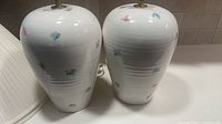 Two white ceramic lamps with floral pattern front view