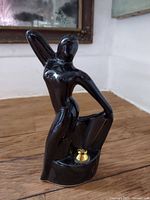 Front view of glossy black ceramic nude pen holder showing brass-tone pen mount