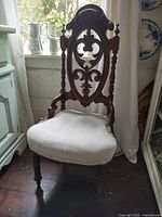 Front view showing carved walnut backrest and upholstered seat