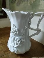 Full view of white porcelain jug showing shape, handle, floral relief