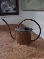 Side view of brass watering can showing diamond pattern, handle and spout
