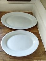 Two white oval platters on wood surface