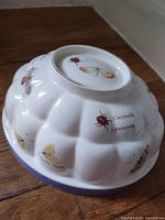 Full view of underside of Wedgwood jelly mould showing fluted form, insect illustrations, Latin names, and lavender band