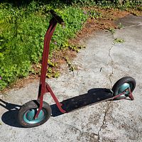 Full side view of vintage child scooter showing wooden deck, red metal frame, teal hubs, black Firestone tires