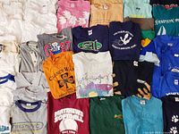 Overhead view of assorted T-shirts and sweatshirts showing graphics and colors