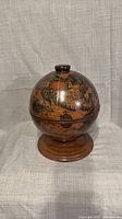 Full view of wooden globe trinket box on pedestal