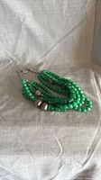 Necklace coiled to show multiple strands of green beads and silver-tone spacers