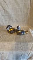 Both brass duck figurines side by side, showing left profiles