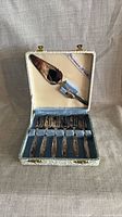 Open case showing seven dessert forks and cake server