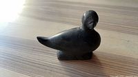 Full view of soapstone bird carving on wooden surface