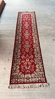 Full view of red floral runner rug showing pattern, border, and fringe