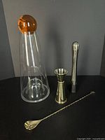 All items grouped: Fia decanter with amber ball, gold jigger, stainless muddler, twisted bar spoon