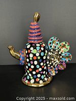 Front view of multicolour polka-dot ceramic teapot with gold spout and petal handle