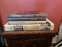Stacked view of the four hardcover art books showing spines: Leonardo, The Art of Robert Bateman, Christopher Pratt, Norman Rockwell