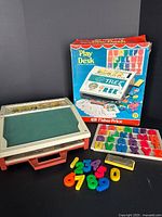 Desk, box, letters, numbers, eraser visible