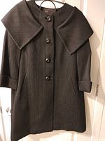 Front view of black herringbone coat showing buttons, collar, cuffs