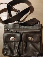 Front view showing two flap pockets, top zip and strap