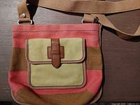 Front view showing striped canvas, front pocket, leather trim, strap attachment