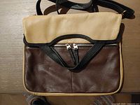 Front of tan and brown pebbled leather bag with black strap and exterior zip pocket