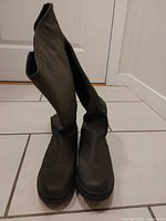 Front view of both olive green knee-high boots standing upright