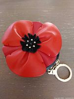 Front view showing red flower appliqué on round black leather purse