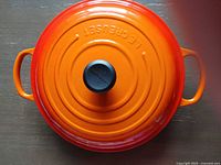 Top view of orange lid showing concentric rings, knob, Le Creuset marking