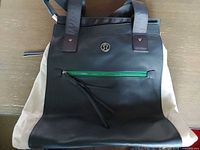 Front view of tote showing logo, green zip pocket, two-tone color