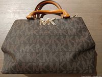 Front view of Michael Kors brown monogram satchel bag showing MK logo, handles, canvas pattern