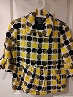 Front view of yellow/black/white polka dot double-breasted blazer on hanger