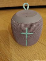 Front view of Ultimate Ears Wonderboom speaker showing lavender fabric, teal volume plus sign