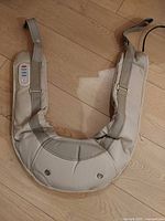 Front view of beige U-shaped massager showing LCD control panel and arm straps