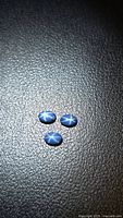 Three blue oval cabochon sapphires on black background
