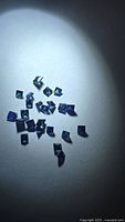 Group of loose square-cut blue sapphires under spotlight