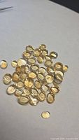 Pile of oval golden citrine cabochons on white background