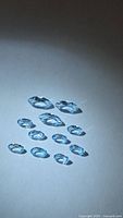 11 faceted sky-blue topaz stones arranged on neutral background