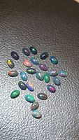 Group of small oval black opal cabochons showing play of color