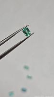 Single emerald held by tweezers