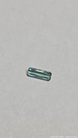 Rectangular octagon-cut blue-green tourmaline on neutral background