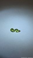 Pair of apple green round peridot gemstones on neutral background