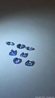 Seven loose tanzanite gemstones on neutral background