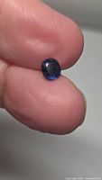 Sapphire held between fingers, showing overall size and color