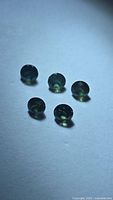 Five round green sapphires on light background