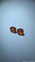 Both oval Spessartite garnets side by side on white background