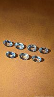 Seven oval aquamarine gemstones on brown background