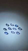Nine oval blue-violet faceted stones arranged on neutral background